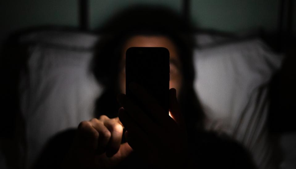 A man using mobile phone at night in bed