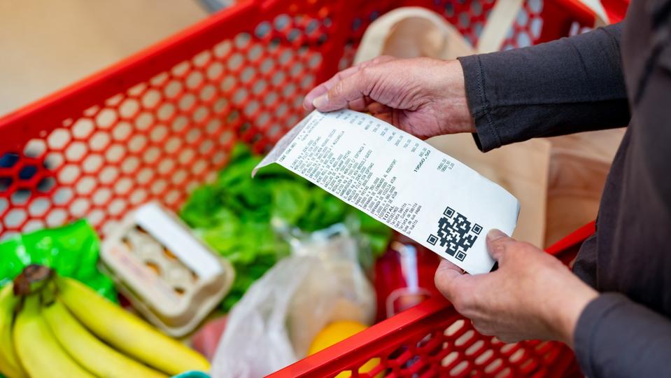 Close up of unrecognizable customer checking her receipt after purchasing groceries in the supermarket
