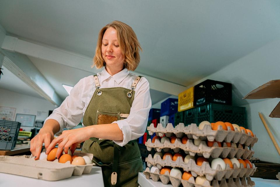 Cheerful Caucasian Woman Packing Fresh Farm Chicken Eggs at a Local Small Business Farm-to-Table Supplier Warehouse in Colorado
