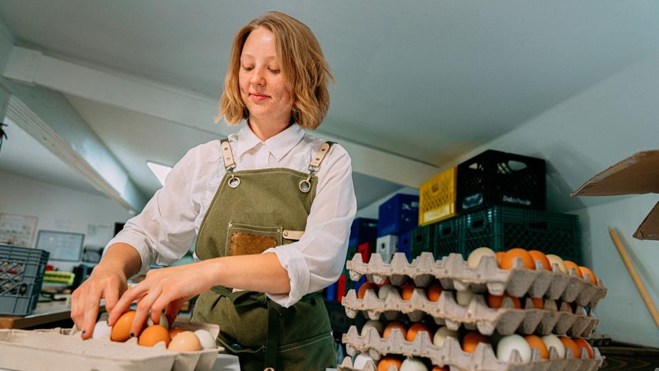 Cheerful Caucasian Woman Packing Fresh Farm Chicken Eggs at a Local Small Business Farm-to-Table Supplier Warehouse in Colorado