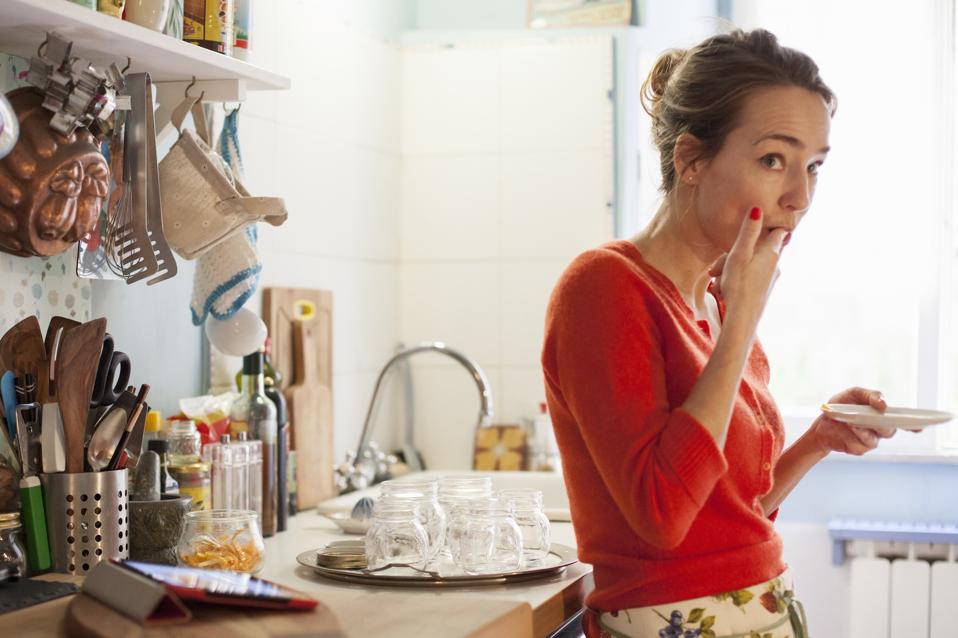 Woman tasting freshly made marmalade from saucer
