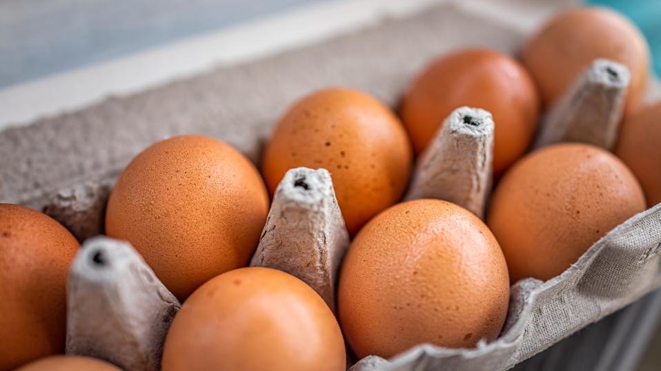 Closeup macro of pasture raised farm fresh dozen brown eggs store bought from farmer in carton box container with speckled eggshells texture