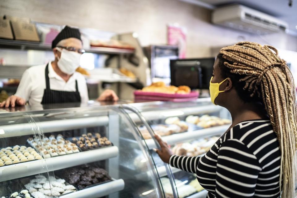 Young woman ordering some groceries in the bakery using face mask