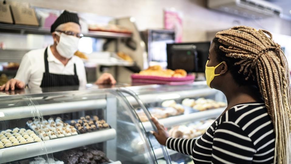 Young woman ordering some groceries in the bakery using face mask