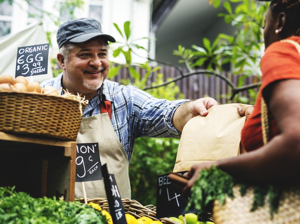Greengrocer selling organic fresh agricultural product at farmer market