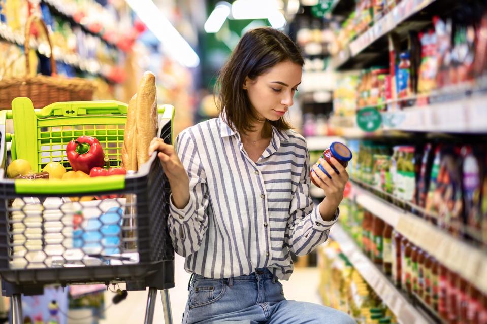 Young woman with the cart shopping in hypermarket