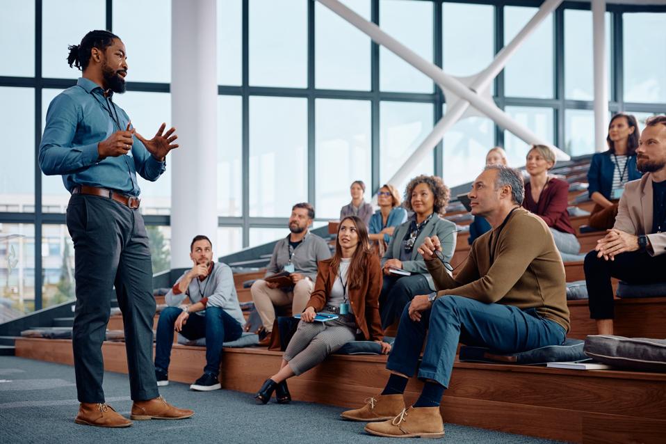 A businessman talking to large group of entrepreneurs during an education event.