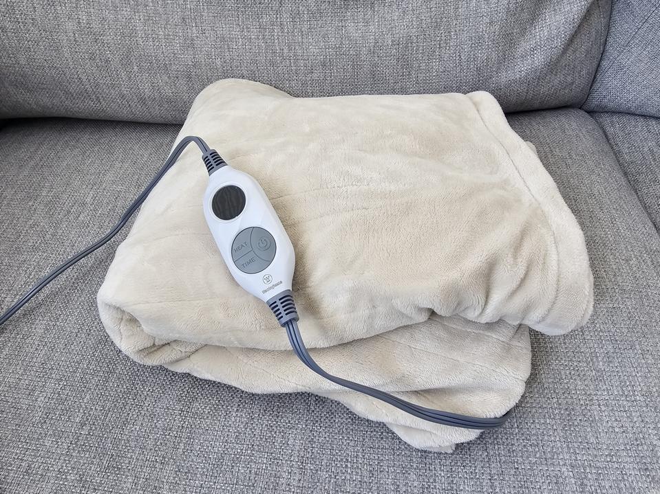 the westinghouse heated blanket in the color beige folded up with its remote on top of it