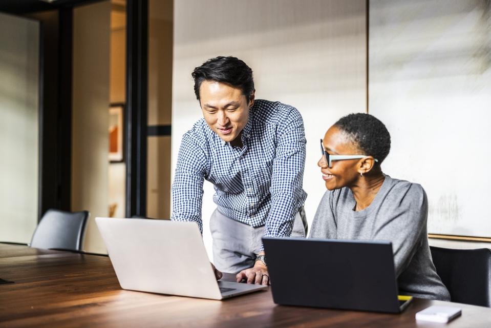 Business colleagues working on laptops in modern conference room