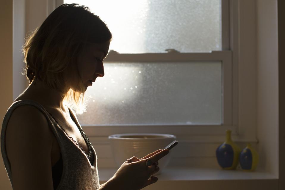Silhouette of woman looking at smart phone