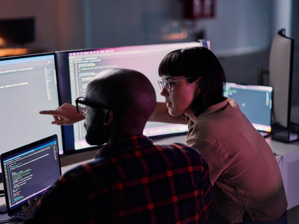 Creative developer, coding and team idea programming on computer in software or application development at office. 2 IT co-workers code on laptop or technology for testing, web design or online startup