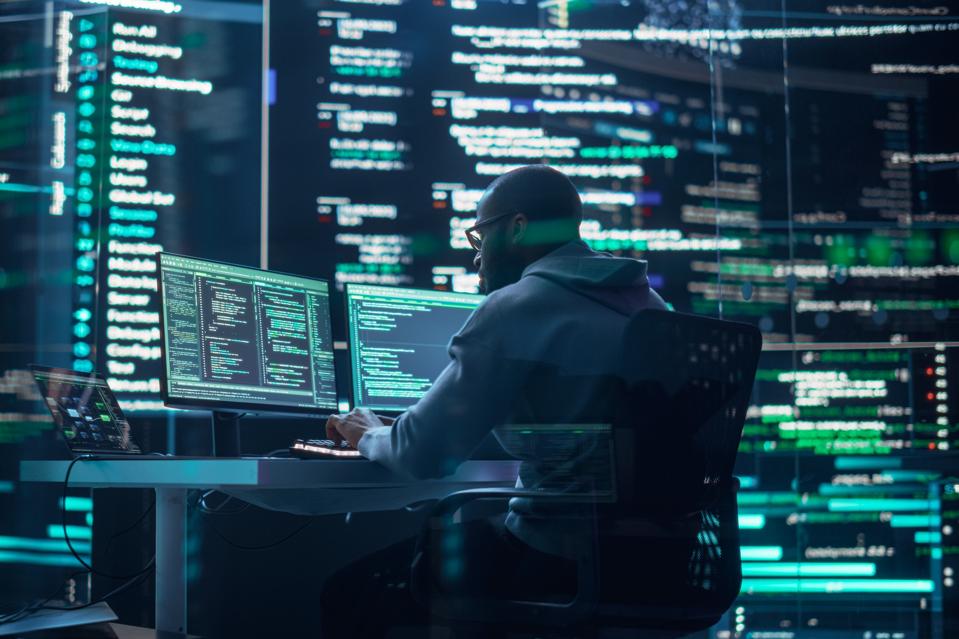 Black Male Developer Thinking and Typing on Computer, Surrounded by Big Screens Showing Coding Prompts. Professional Programmer Creating Software, Running Coding Tests. Futuristic Programming Concept
