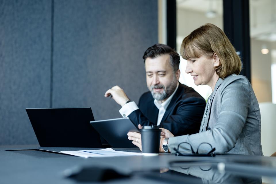 A Good Risk Management Strategy Can Help Protect Your Brand. Senior Businesswomen in executive meetings show business vision on a tablet computer with businessmen in a meeting room.