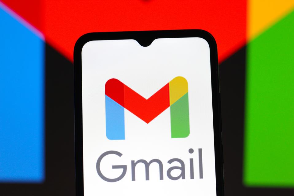 Gmail logo is seen displayed on smartphone, the background of image is in Google brand colors.