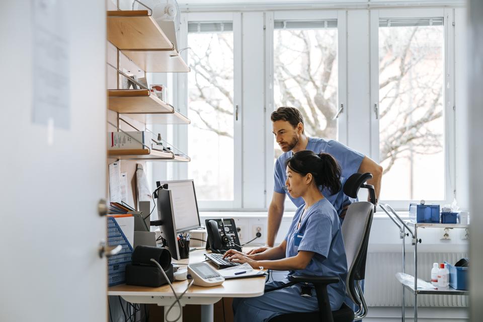 Focused male and female medical experts working on computer in clinic