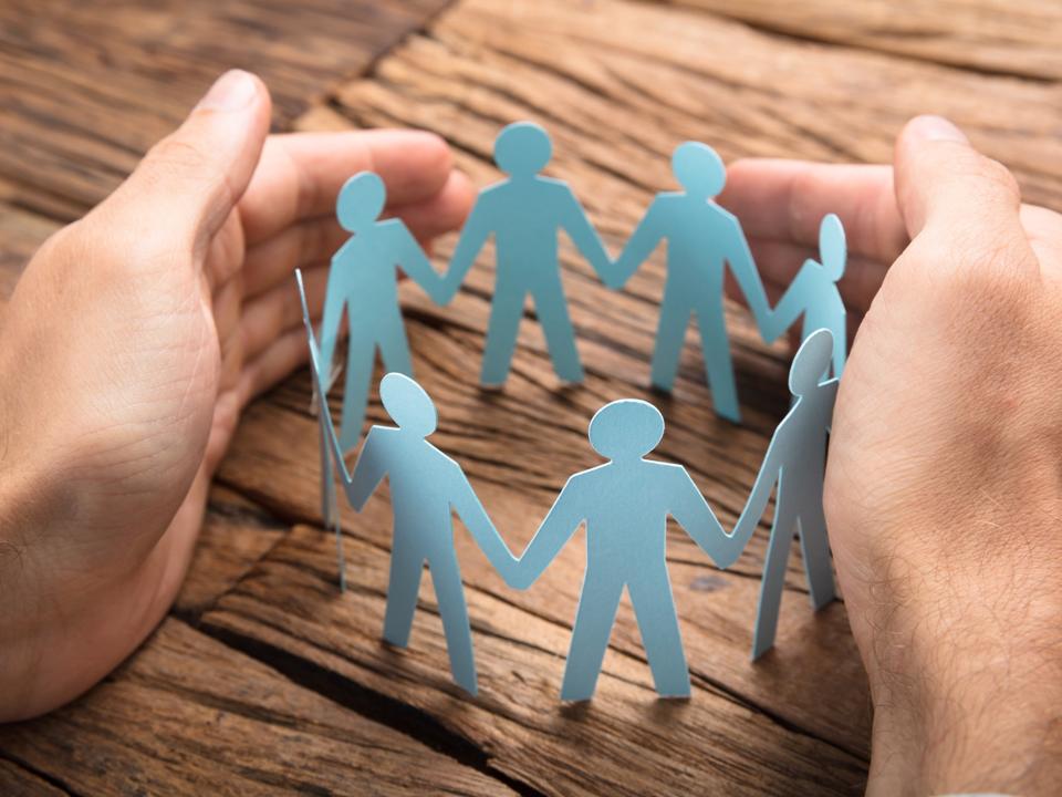 Businessman's Hands Covering Paper Team On Table