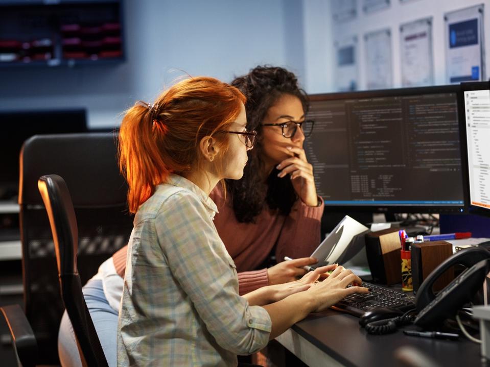 Two female programmers working on new project.They working late at night at the office.