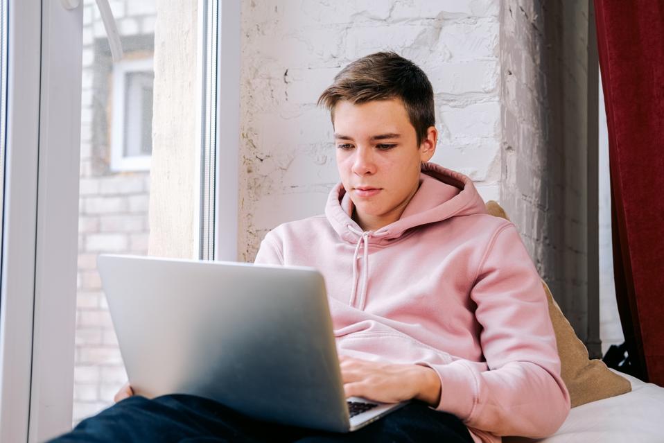 teen boy using his laptop to create a digital product to sell