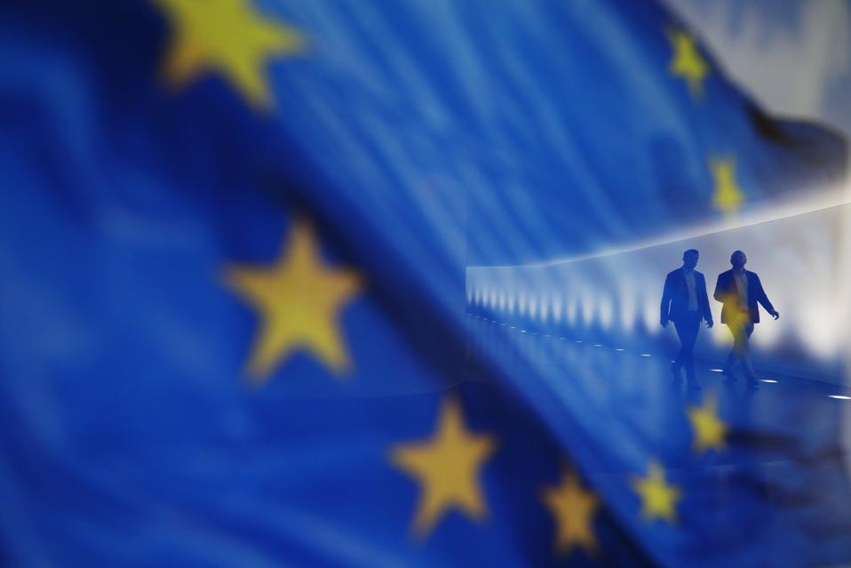 People walk by a European flag.