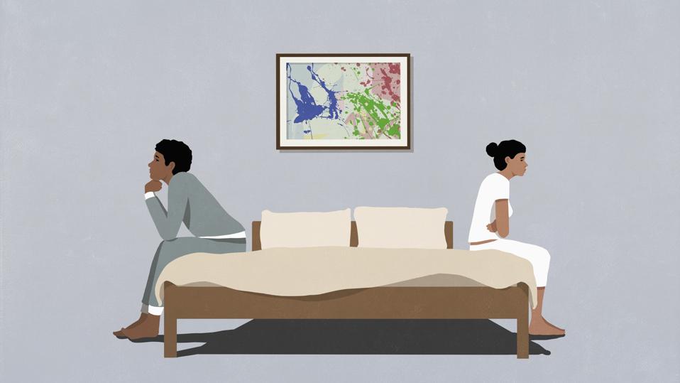 Frustrated couple sitting back to back at opposite edges of bed