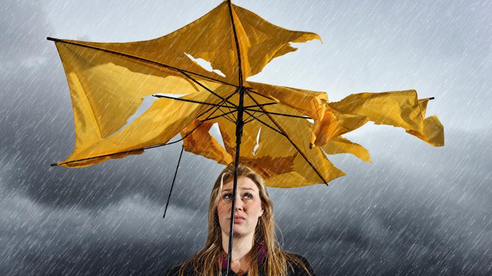Beautiful unhappy blonde with ruined umbrella getting soaked in thunderstorm