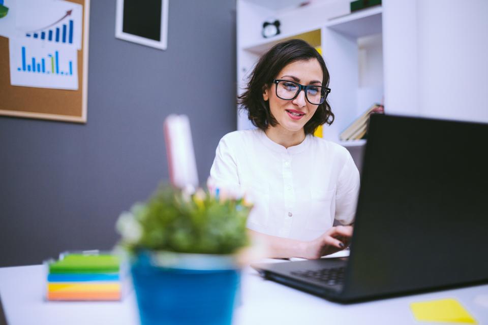 Woman in small nonprofit office working on a laptop. Nonprofit technology tools.