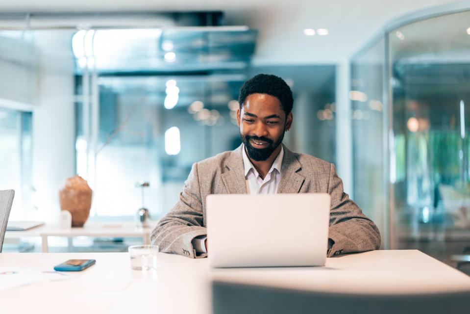 Smiling businessman working on laptop in modern office