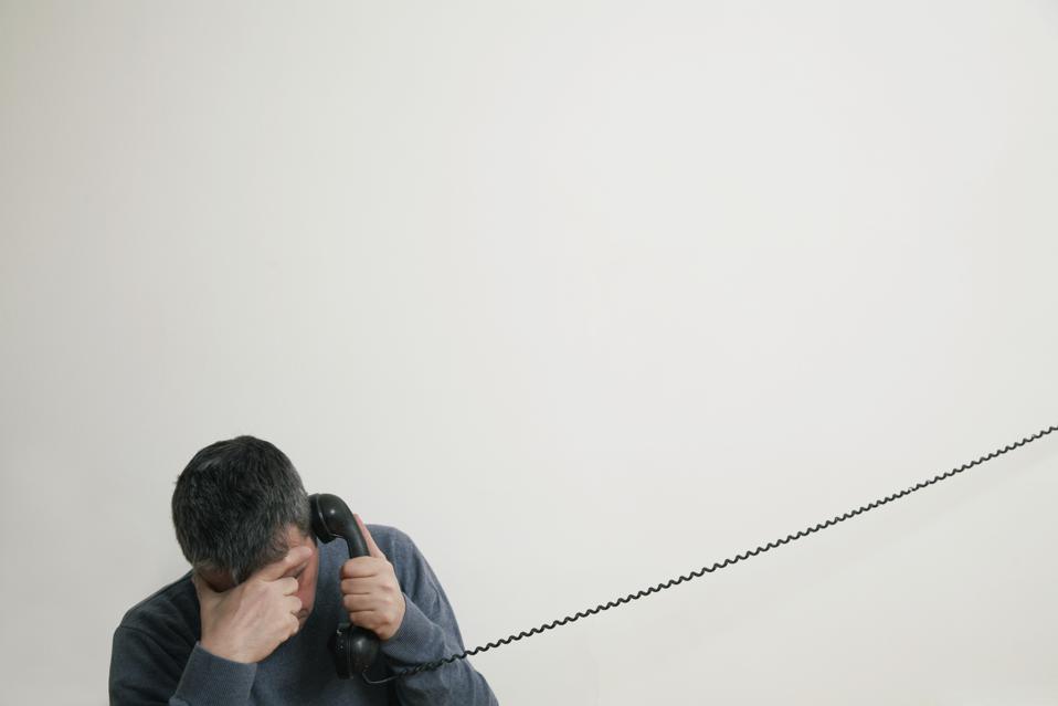 Man sitting on stairs using telephone, hand to forehead