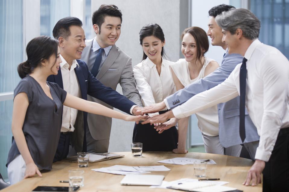 Confident business people stacking hands in meeting room