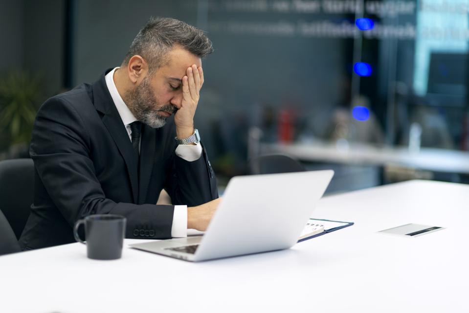 Worried businessman reading bad news on laptop in the office