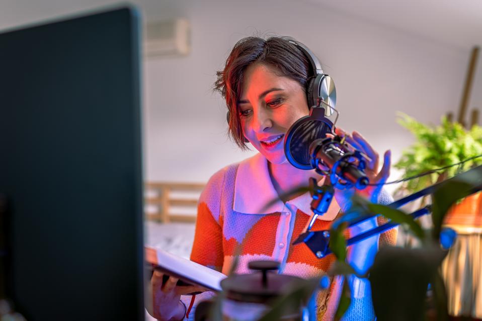 Beautiful young woman recording podcast