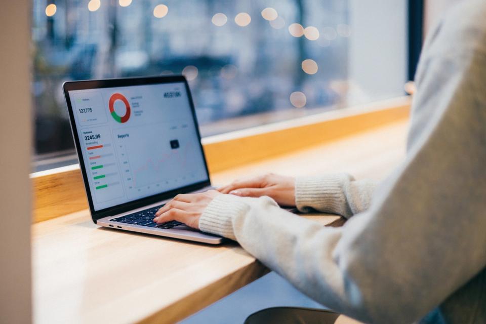 A close-up image of a person working on a laptop displaying business analytic charts and graphs, illustrating data literacy.