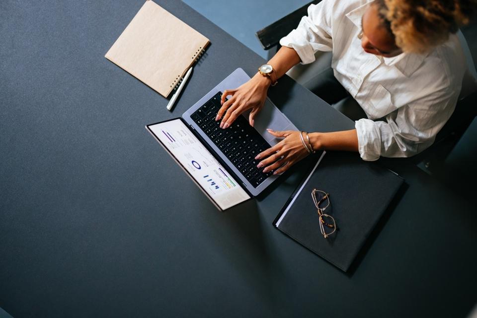 High Angle View Of Unrecognizable Woman Typing Business Report On A Laptop Keyboard In The Cafe