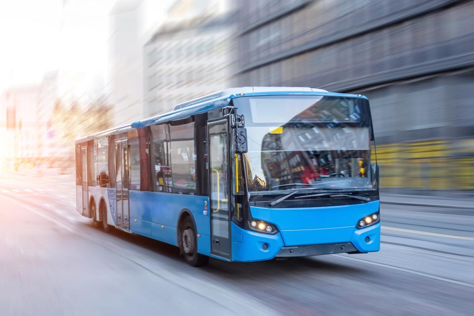Blue bus moving on the road in city in early morning.