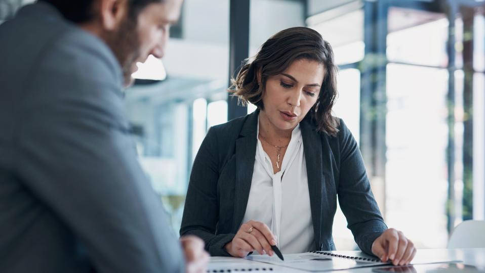 Business man, woman and paperwork with discussion for deal, agreement and proposal for b2b collaboration. People, staff and meeting with documents for financial strategy, stats and feedback in office