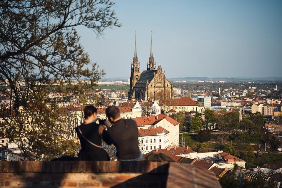 Mladý pár sedí pod hradem Špilberk a dívá se na Petrov, Brno