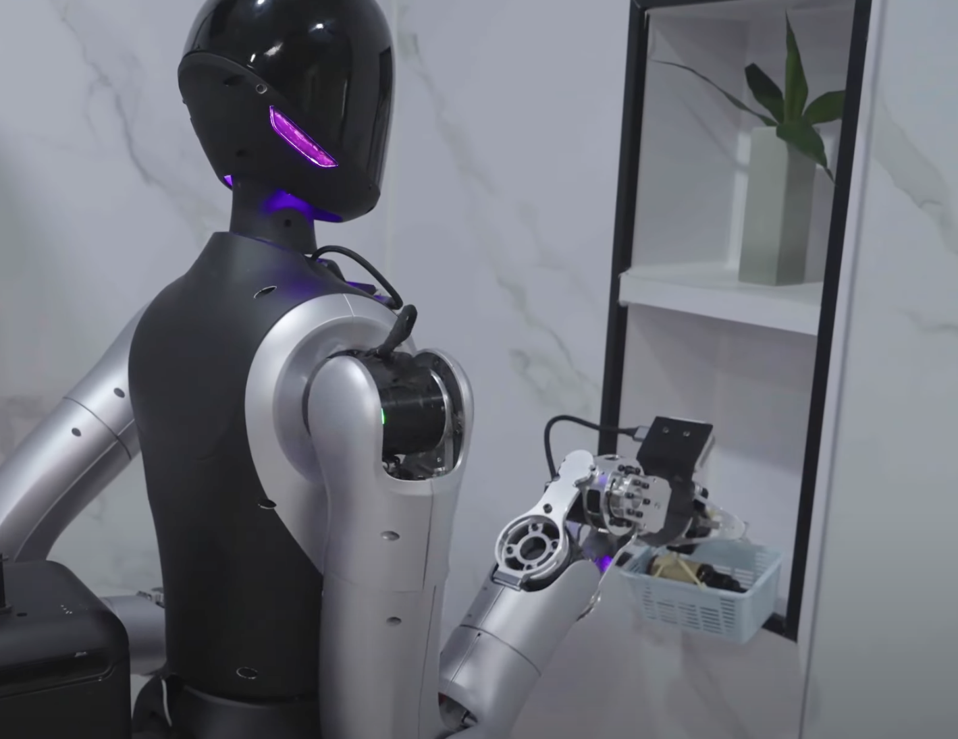 Black and silver humanoid robot places a small caddy of amenities into a shower nook
