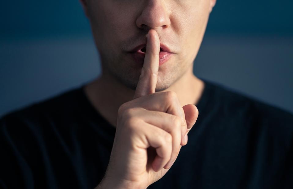 Secret and silence. Quiet silent shh gesture with finger on lips. Man doing expression with hand on mouth. Taboo topic, censorship or freedom or speech. Conspiracy theory.