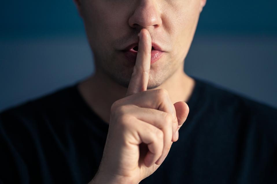 Secret and silence. Quiet silent shh gesture with finger on lips. Man doing expression with hand on mouth. Taboo topic, censorship or freedom or speech. Conspiracy theory.