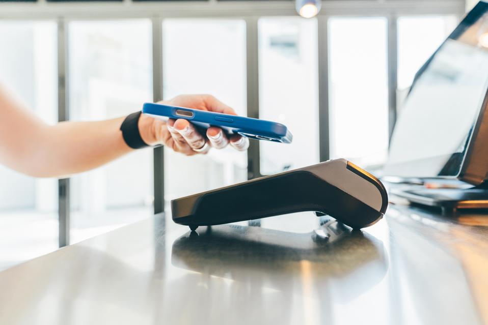 Woman pays with a phone in a cafe.