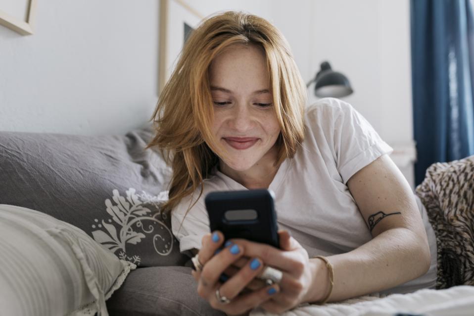Gen Z woman smiling at her phone