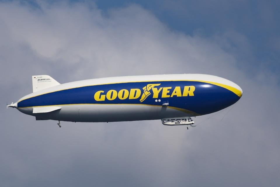 Goodyear liveried blimp in the sky against clouds and a blue sky