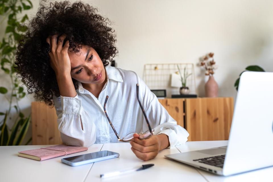 Young African American woman feeling exhausted and depressed sitting in front of laptop. Work burnout syndrome.