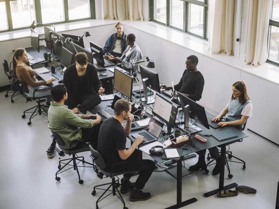 High angle view of male and female programmers working on computers at desk in office