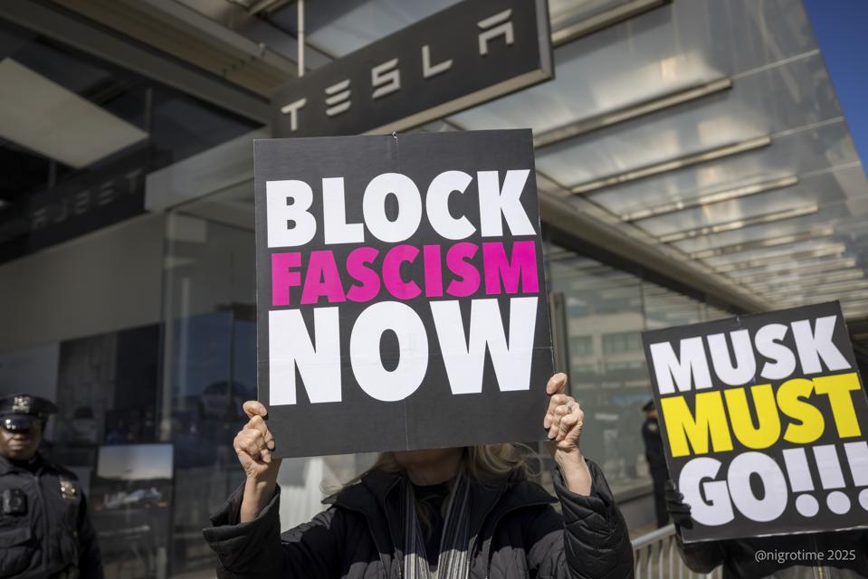 A protestor outside a Tesla showroom in Manhattan holds a...