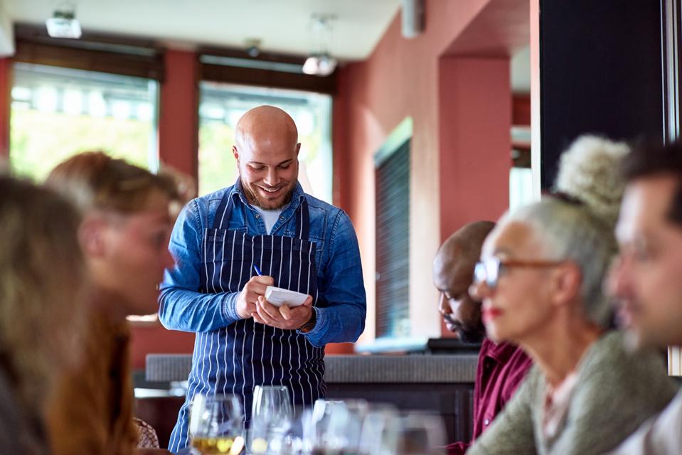 Cheerful waiter taking orders in restaurant