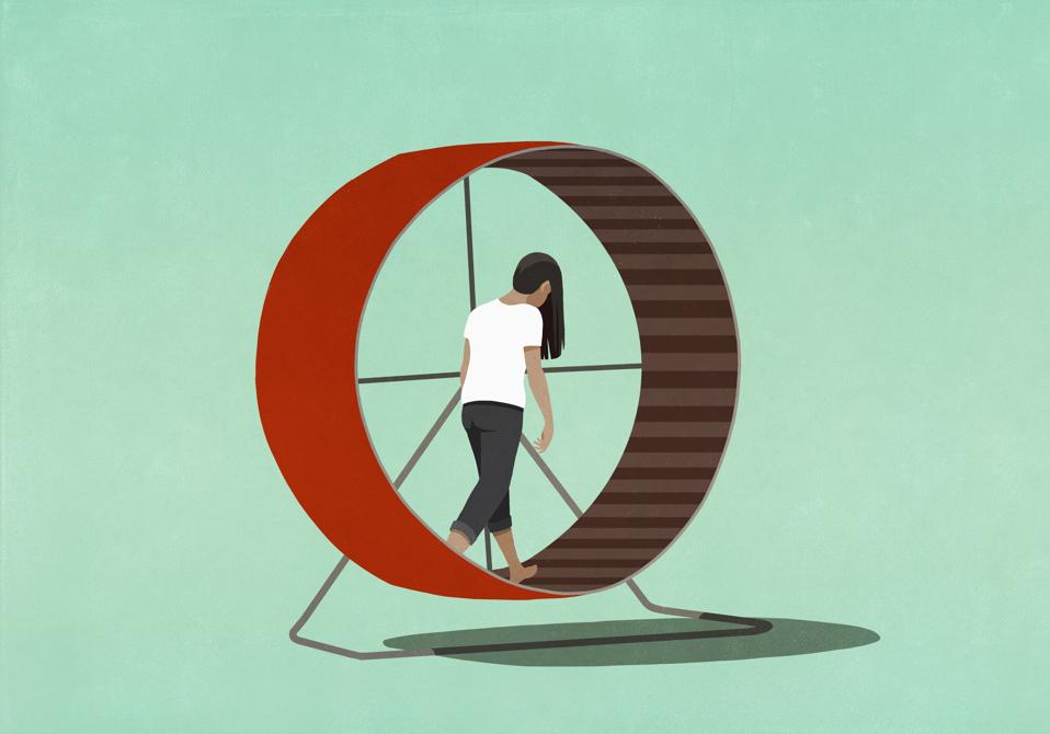 A tired woman walks inside a red hamster wheel.