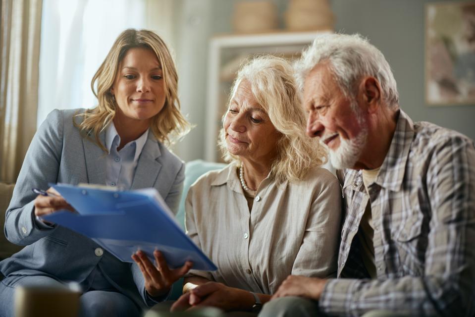 Female agent and her mature customers reading plans at home.