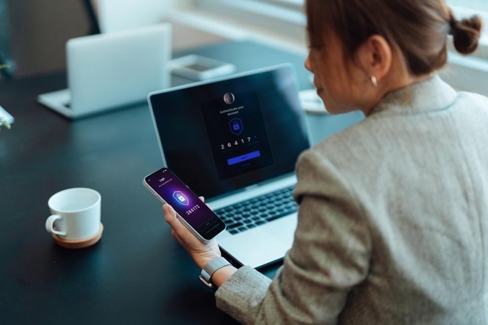 Asian businesswoman logging in online account with Two-Factor Authentication (2FA) security system on smart phone and laptop