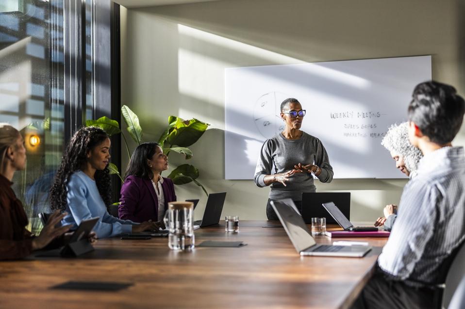 Female business owner speaking to office workers in modern conference room